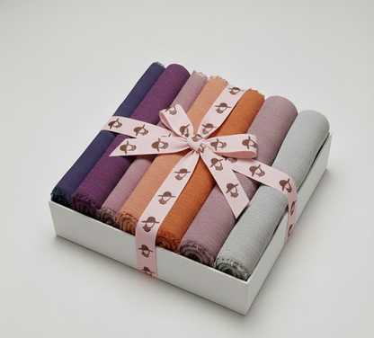 “Set of folded crimp fabric swatches in various colors tied with a pink ribbon, presented in a white Graceful Layers box.”