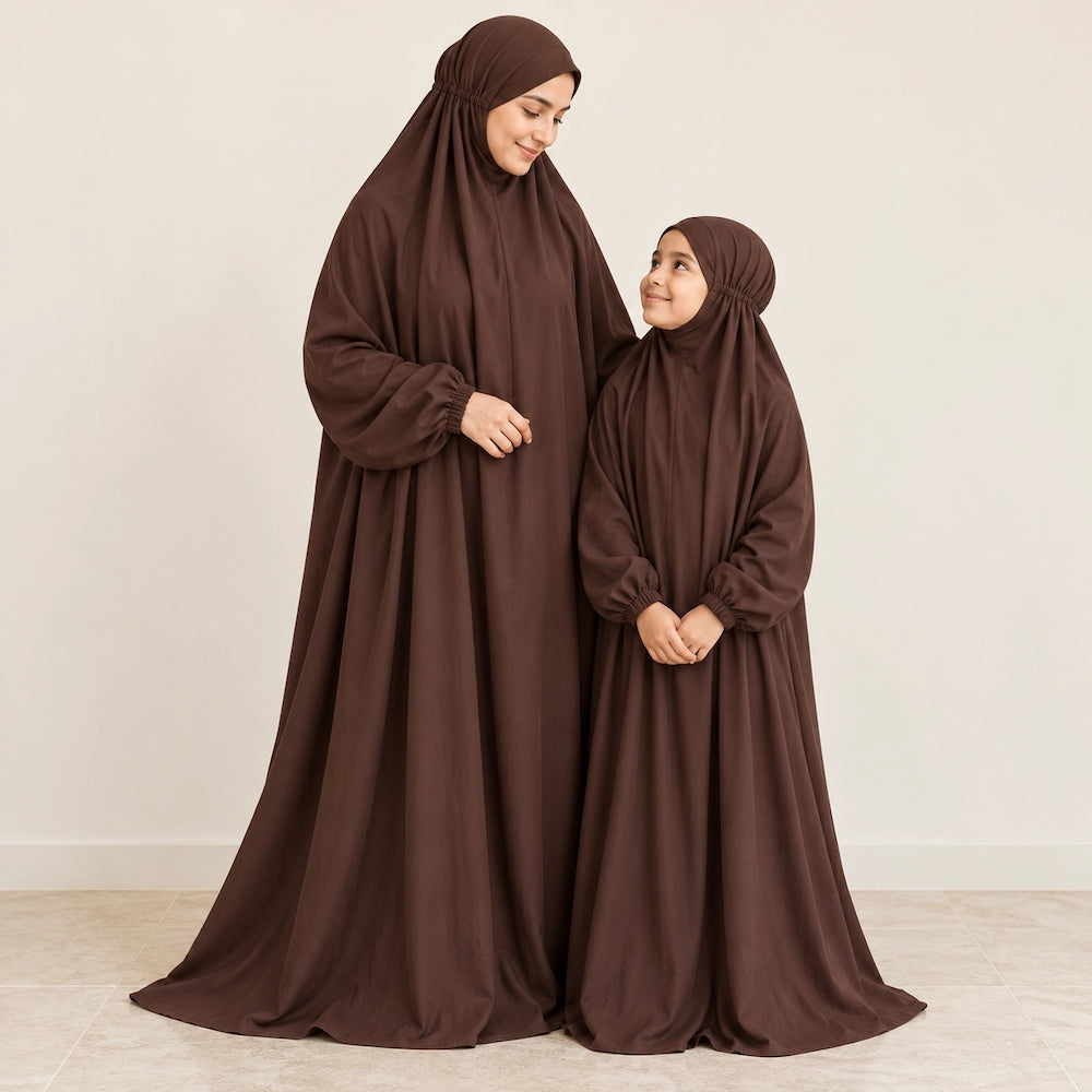 Mother and daughter smiling at each other in matching chocolate brown namaz chaddars with elastic wrist cuffs.