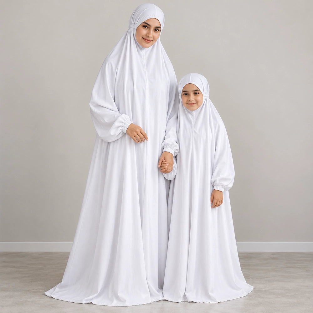 Mother and daughter wearing matching plain white namaz chaddars with elasticated cuffs and fitted head coverings.