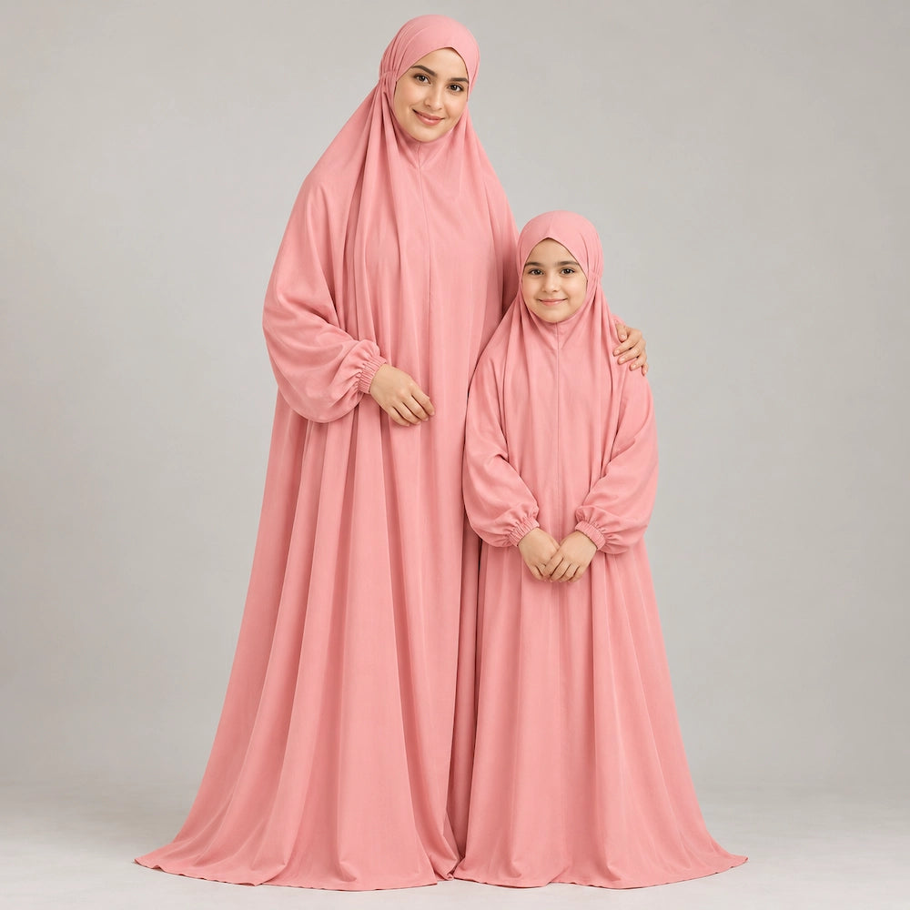 Mother resting a hand on her daughter's shoulder while both wear matching plain peach prayer chaddars.