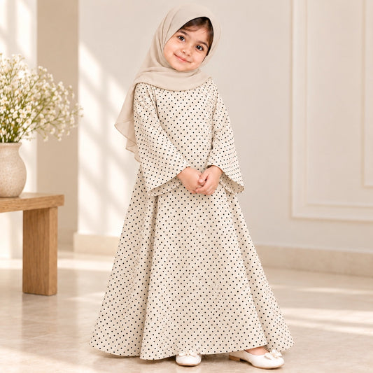 Girl wearing a cream abaya with tiny black polka dots, wide bell sleeves and a flared hem, styled with a cream hijab.