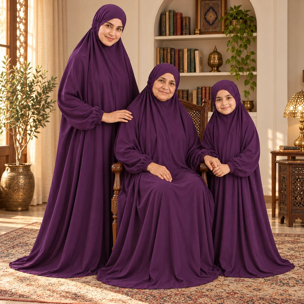 Grandmother seated in a wooden chair with her daughter and granddaughter beside her, all wearing deep purple namaz chaddars.