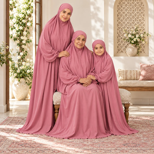 Grandmother seated on a bench with mother and granddaughter beside her, all wearing matching dusty rose prayer chaddars.