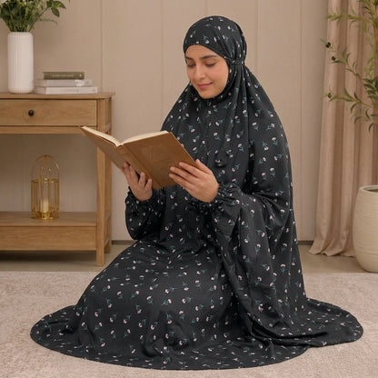 A woman wearing a black modest namaz chaddar with a small floral print.
