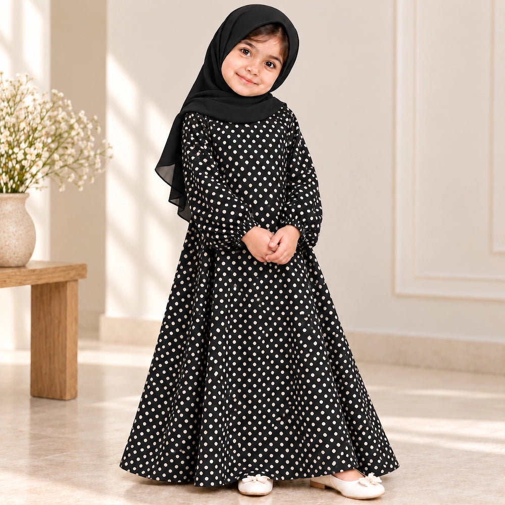 Girl wearing a black abaya with cream polka dots, wide flared sleeves and an umbrella-style hem, paired with a black hijab.