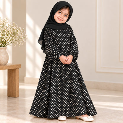 Girl wearing a black abaya with cream polka dots, wide flared sleeves and an umbrella-style hem, paired with a black hijab.