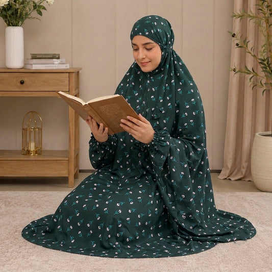 Woman in a black and green namaz chaddar with white floral patterns