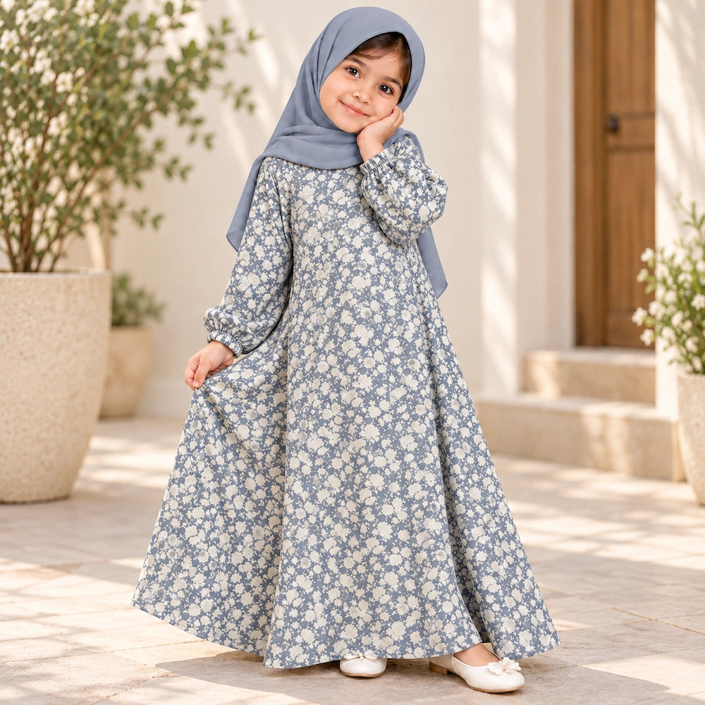 Girl wearing a blue-grey abaya with ivory floral print, gathered elastic cuffs and a wide hem, styled with a blue-grey hijab.