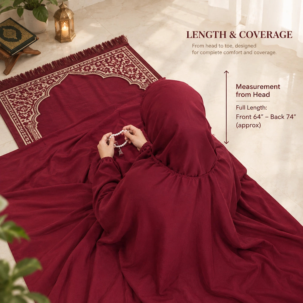 Woman wearing a plain maroon namaz chaddar, seated beside a prayer mat and holding prayer beads