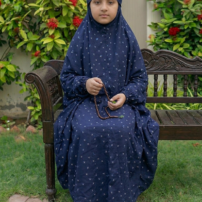 kids namaz chaddar in blue with white patterns, sitting on a wooden bench outdoors.