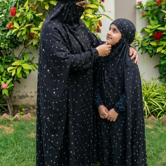 Mother daughter in matching black namaz chaddar with blue  and white flowers