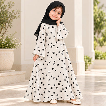 Girl wearing an ivory abaya with scattered black stars, wide bell sleeves and a flared umbrella-style hem, paired with a black hijab.